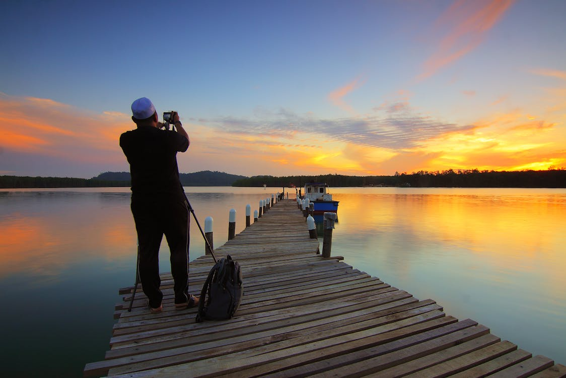 take photos around water with a camera on a dock during sunset over a calm lake