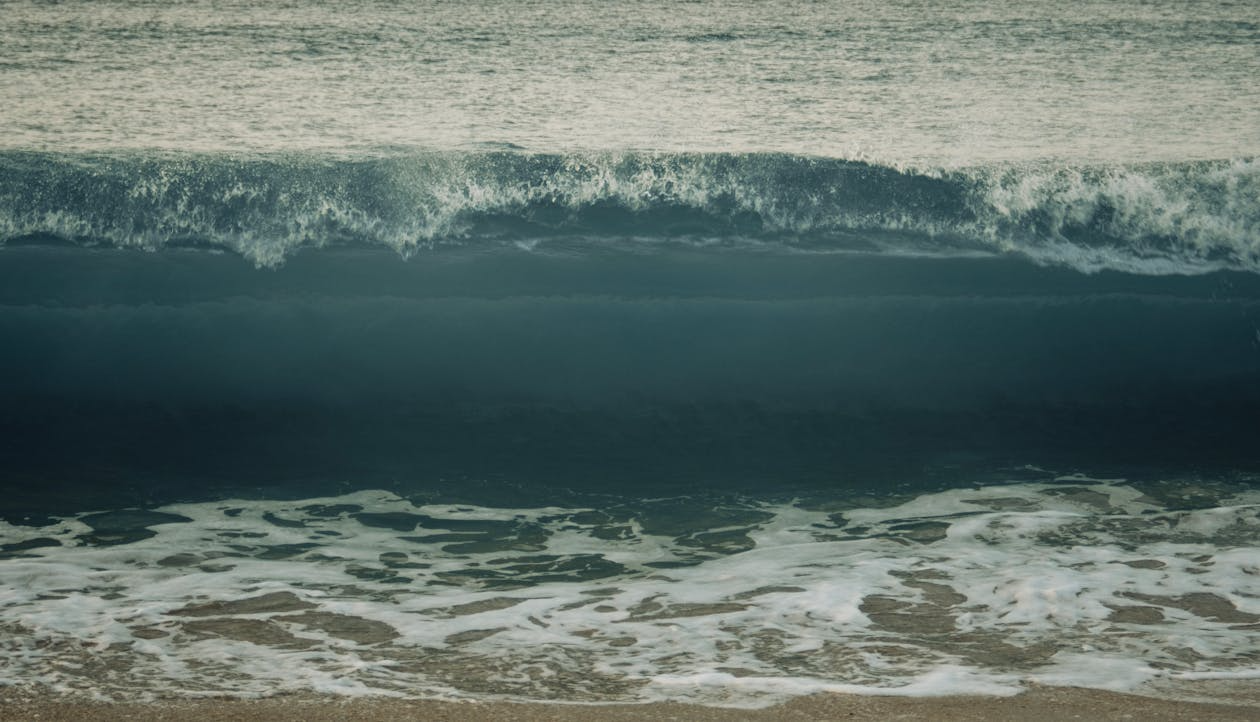how tsunamis form with a large dark wave moving toward the shore