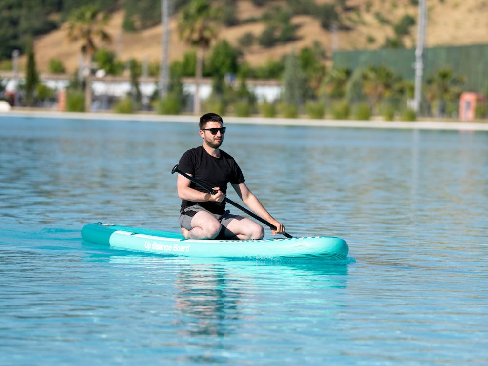 water sports for beginners with a paddleboarder learning on calm flat water