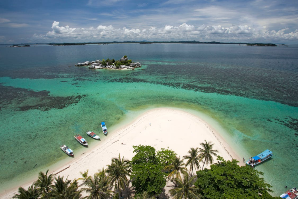 hidden island destinations with white sand, turquoise water, palm trees, and small boats near shoreline