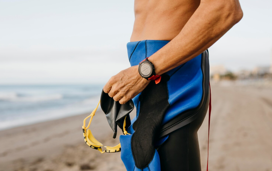 Waterproof tech for travel with a swimmer wearing a fitness watch while holding goggles