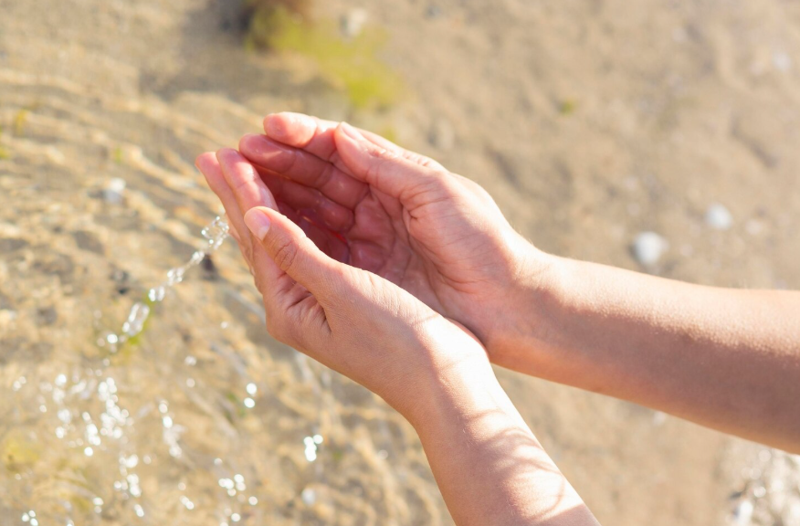 Why can’t you drink ocean water shown by hands cupping water near a sandy shoreline.