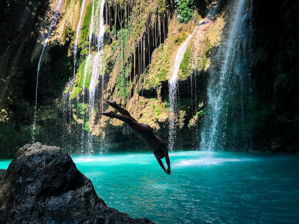 Swimmable waterfalls showing a person entering a plunge pool beneath cascading falls.