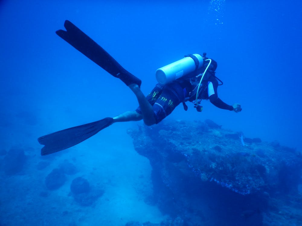 How water pressure works shown by a scuba diver descending into deep blue ocean water.