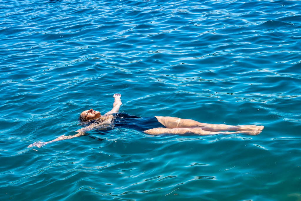 Why you float in salt water shown by a person floating calmly on blue ocean water.