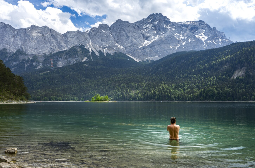 cold water destinations with a swimmer in a clear alpine lake surrounded by mountains