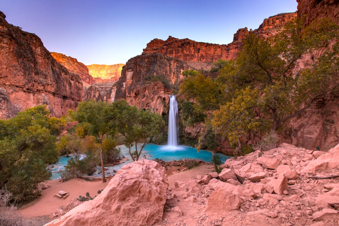hidden swimming holes with a turquoise waterfall pool surrounded by red canyon cliffs